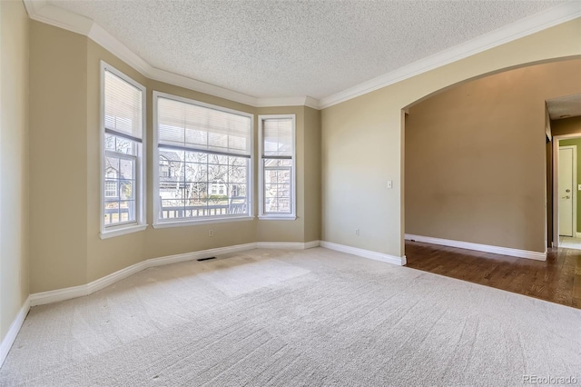carpeted empty room with arched walkways, crown molding, and a textured ceiling