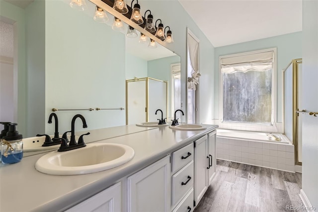 full bath featuring a sink, a bath, double vanity, and wood finished floors