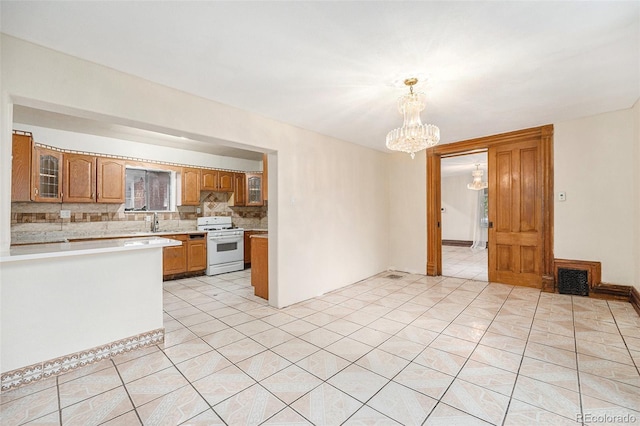 7 Elati St, Denver, CO 80223 - kitchen with gas range gas stove, light countertops, a chandelier, tasteful backsplash, and glass insert cabinets
