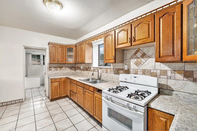 7 Elati St, Denver, CO 80223 - kitchen with white range with gas stovetop, brown cabinetry, glass insert cabinets, and decorative backsplash