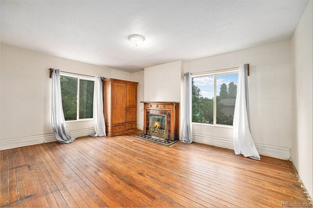 7 Elati St, Denver, CO 80223 - unfurnished living room featuring light wood-type flooring, healthy amount of natural light, and a tile fireplace