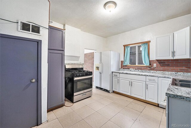 7 Elati St, Denver, CO 80223 - kitchen featuring stainless steel gas range oven, white fridge with ice dispenser, a textured ceiling, light countertops, and white cabinets