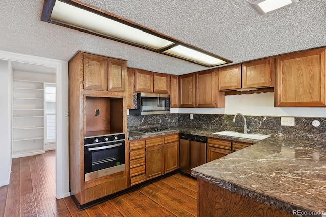 kitchen with sink, dark wood-type flooring, a textured ceiling, and appliances with stainless steel finishes