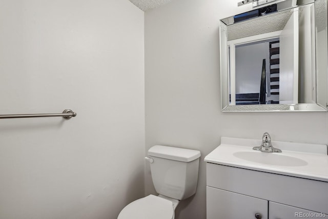 bathroom featuring vanity, a textured ceiling, and toilet