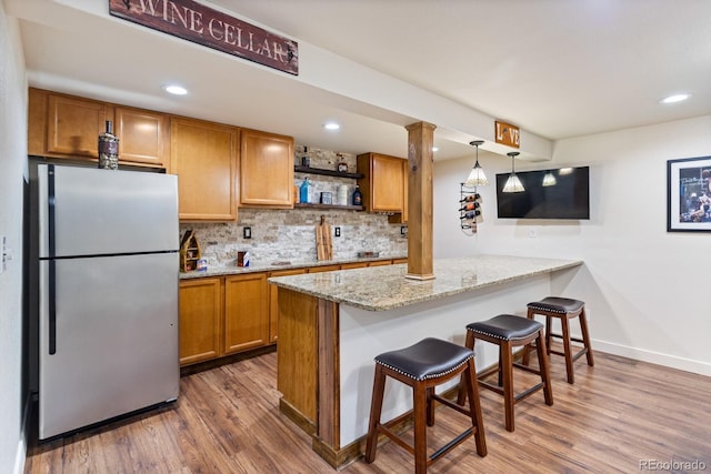 250 W Midway Blvd, Broomfield, CO 80020 - kitchen with freestanding refrigerator, ornate columns, brown cabinetry, tasteful backsplash, and wood finished floors
