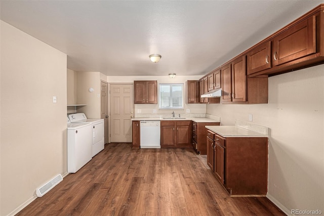 kitchen with dark wood-type flooring, dishwasher, sink, and washer and dryer