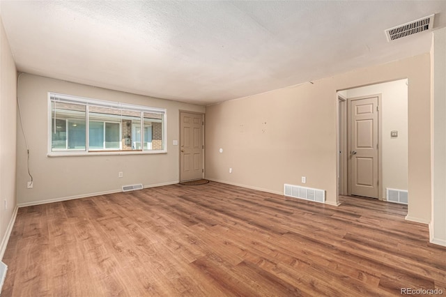 unfurnished room featuring a textured ceiling and light hardwood / wood-style floors