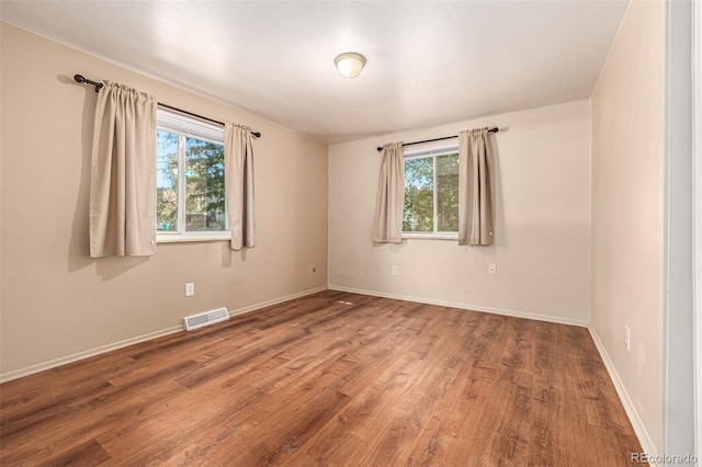 spare room featuring hardwood / wood-style flooring and plenty of natural light