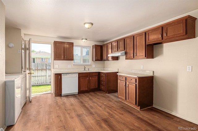 kitchen with dark hardwood / wood-style flooring, dishwasher, washing machine and clothes dryer, and sink