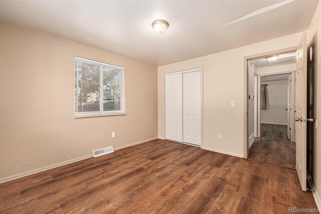 unfurnished bedroom featuring dark wood-type flooring and a closet