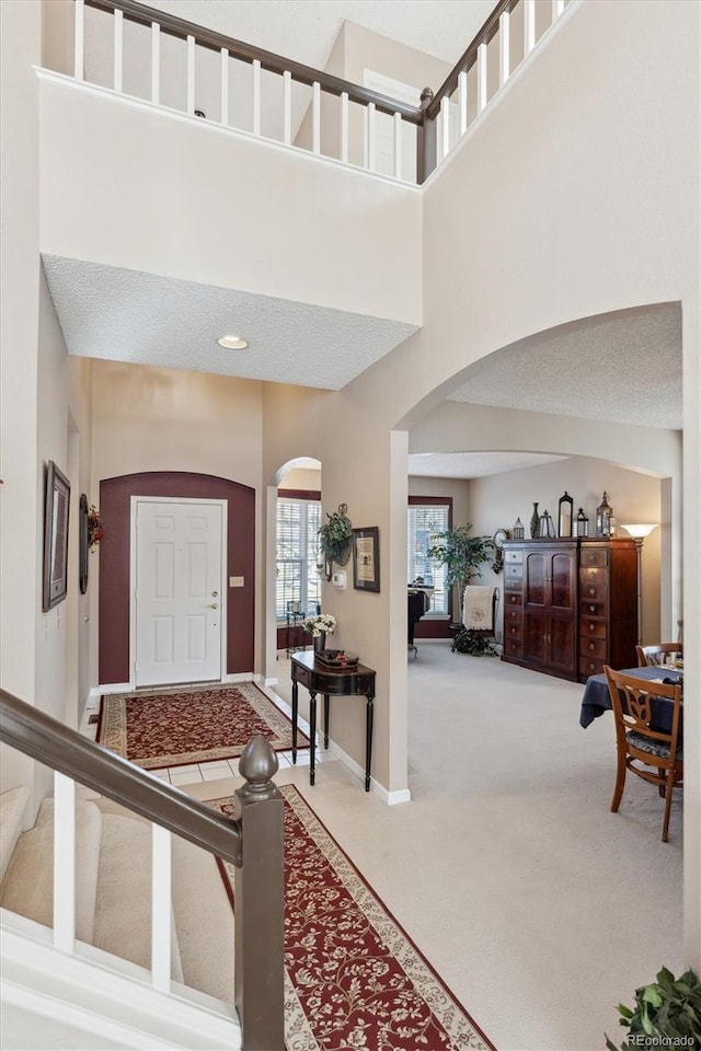 carpeted entrance foyer with a towering ceiling