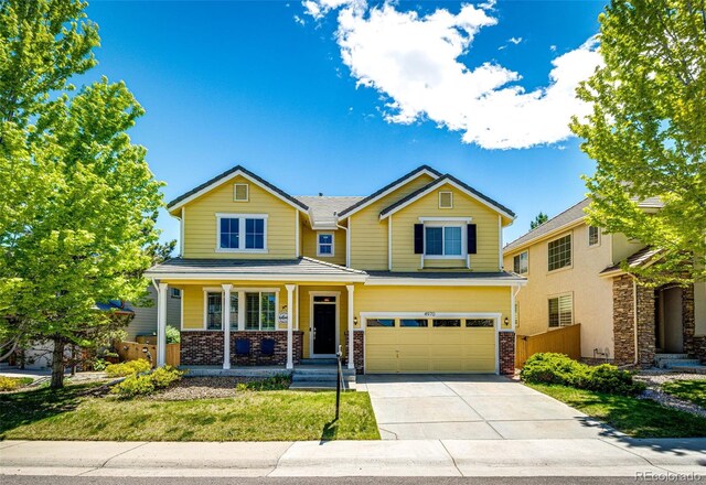 4970 Laurelglen Ln, Highlands Ranch, CO 80130 - view of front of house featuring brick siding, an attached garage, driveway, a porch, and a front yard