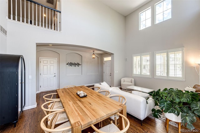 4970 Laurelglen Ln, Highlands Ranch, CO 80130 - dining space featuring high vaulted ceiling, arched walkways, dark wood finished floors, and baseboards