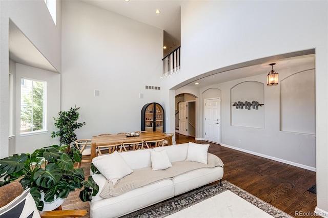 4970 Laurelglen Ln, Highlands Ranch, CO 80130 - living area featuring arched walkways, wood finished floors, a towering ceiling, baseboards, and recessed lighting