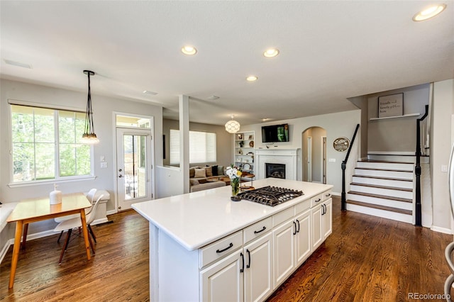 4970 Laurelglen Ln, Highlands Ranch, CO 80130 - kitchen with stainless steel gas stovetop, a fireplace, dark wood-type flooring, recessed lighting, and light countertops
