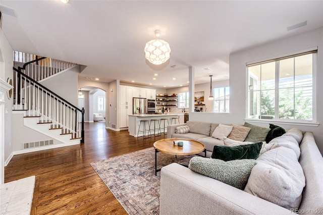 4970 Laurelglen Ln, Highlands Ranch, CO 80130 - living room with arched walkways, dark wood-style floors, stairway, baseboards, and recessed lighting