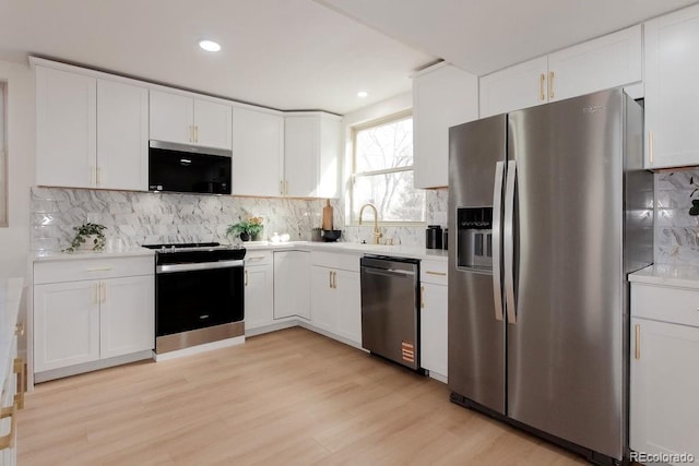 kitchen featuring stainless steel appliances, backsplash, light countertops, and white cabinets