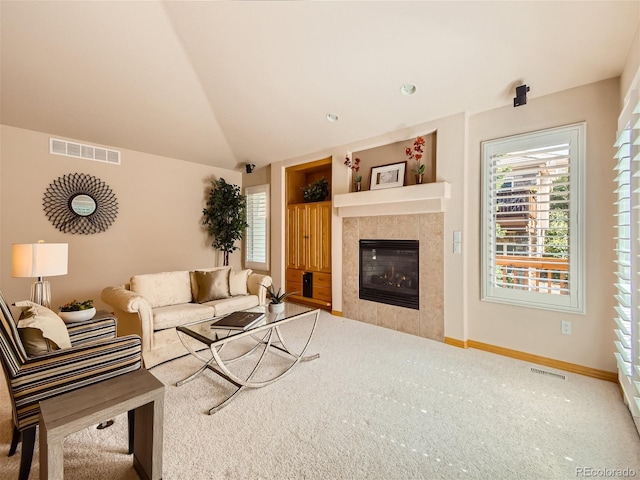 living room featuring carpet flooring, a tile fireplace, and lofted ceiling