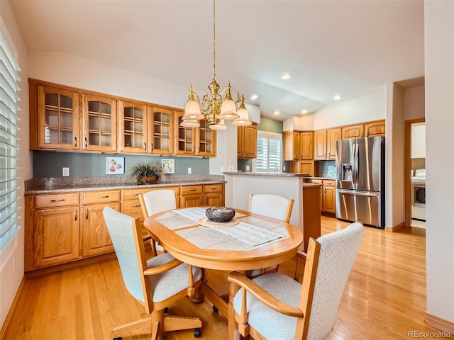 dining area featuring a chandelier, light hardwood / wood-style floors, and washer / dryer