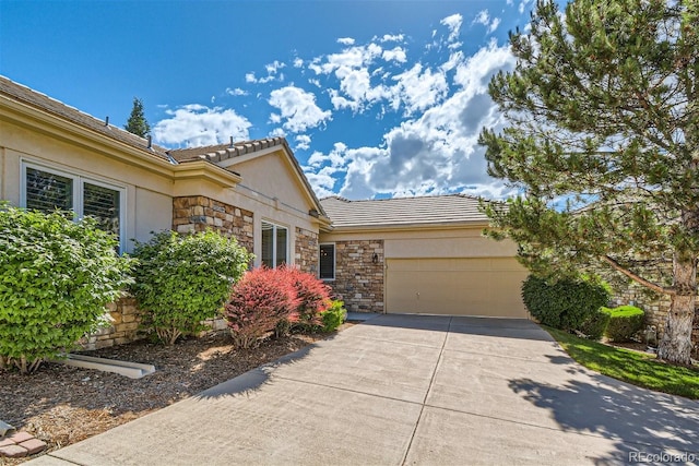 view of front of property with driveway, stone siding, a tiled roof, an attached garage, and stucco siding