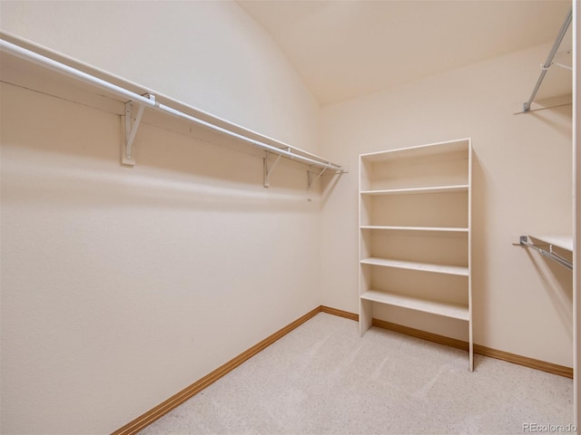 walk in closet with light carpet and lofted ceiling