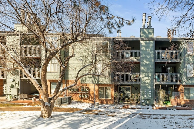 snow covered building with central AC unit