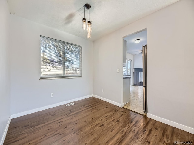 unfurnished room with hardwood / wood-style flooring and a textured ceiling