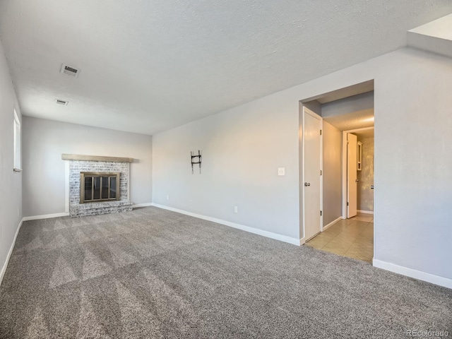 unfurnished living room with a brick fireplace, light colored carpet, and a textured ceiling