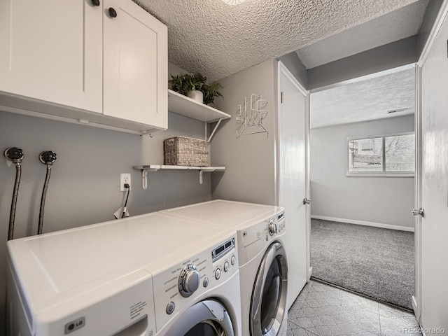 laundry area with cabinets, washing machine and clothes dryer, light carpet, and a textured ceiling