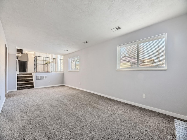 unfurnished living room with carpet floors and a textured ceiling