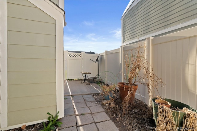 view of side of home featuring a patio, fence, and a gate