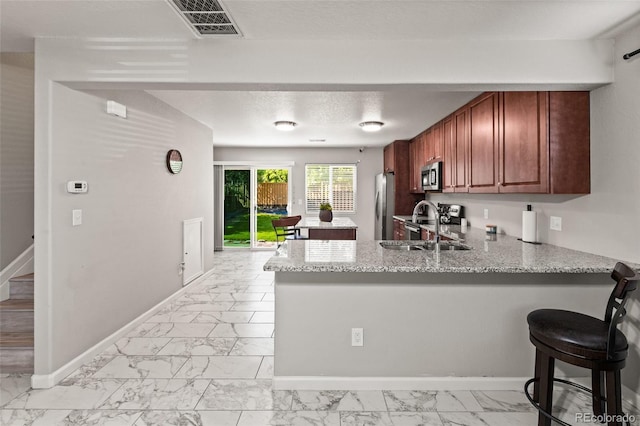 18672 E Chaffee Pl, Denver, CO 80249 - kitchen with stainless steel appliances, light marble finish floors, a peninsula, and light stone countertops