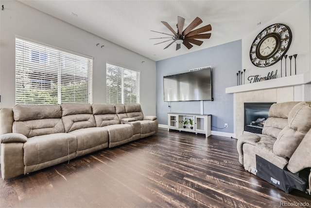 living room featuring dark wood-type flooring, a tiled fireplace, and ceiling fan