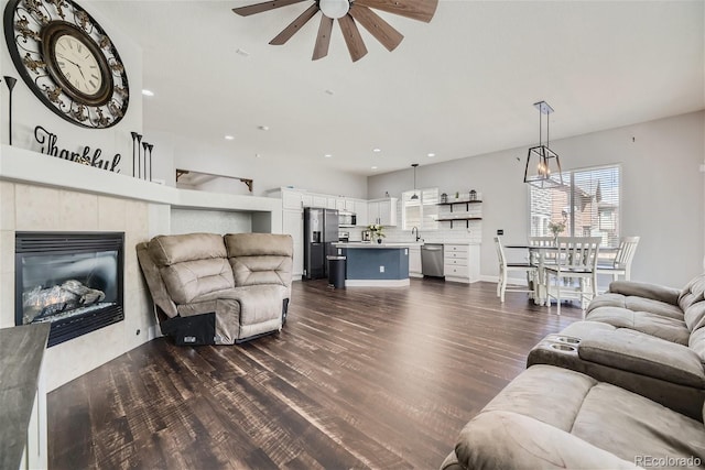 living room with dark wood-type flooring, a fireplace, and ceiling fan