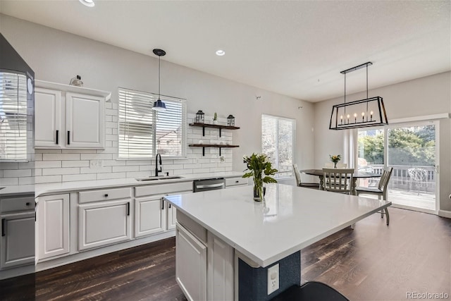 kitchen with white cabinets, tasteful backsplash, sink, and a kitchen island