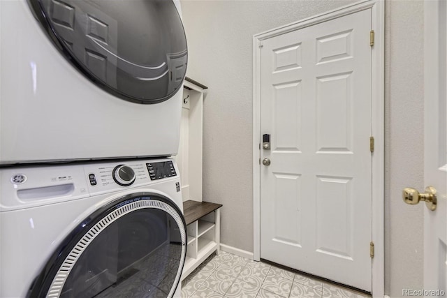 laundry room featuring stacked washer / dryer and light tile patterned floors