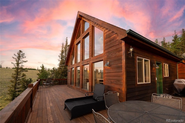 deck at dusk with grilling area and outdoor dining space