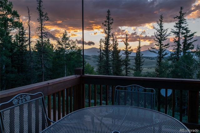 deck at dusk with a mountain view and outdoor dining space