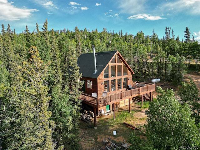 rear view of house with a view of trees and a wooden deck