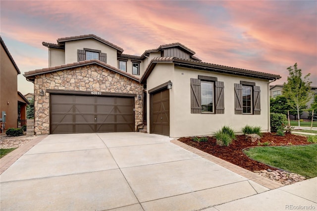 15160 W Iliff Pl, Lakewood, CO 80228 - mediterranean / spanish house with a garage, driveway, stone siding, stucco siding, and a tiled roof
