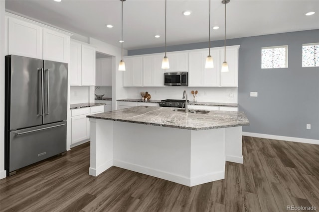 5128 Preserve Pl, Firestone, CO 80504 - kitchen featuring appliances with stainless steel finishes, dark wood-type flooring, a kitchen island with sink, white cabinets, and light stone counters