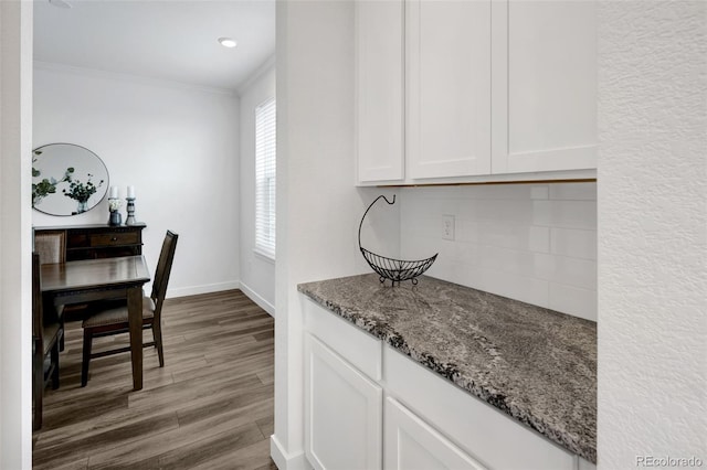 5128 Preserve Pl, Firestone, CO 80504 - kitchen with dark stone counters, light wood-type flooring, white cabinets, crown molding, and decorative backsplash