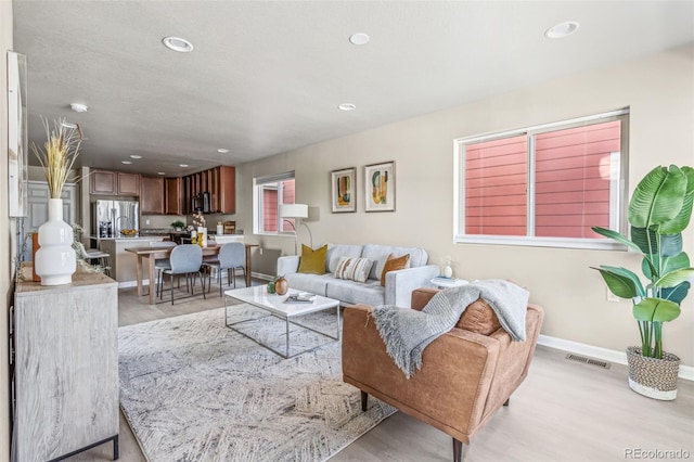 living area featuring recessed lighting, visible vents, and baseboards