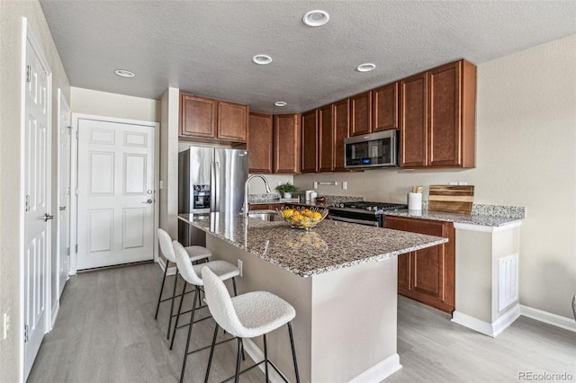 kitchen featuring stainless steel appliances, a breakfast bar, a sink, and light wood-style flooring