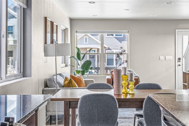 dining room with a textured ceiling, a textured wall, and recessed lighting