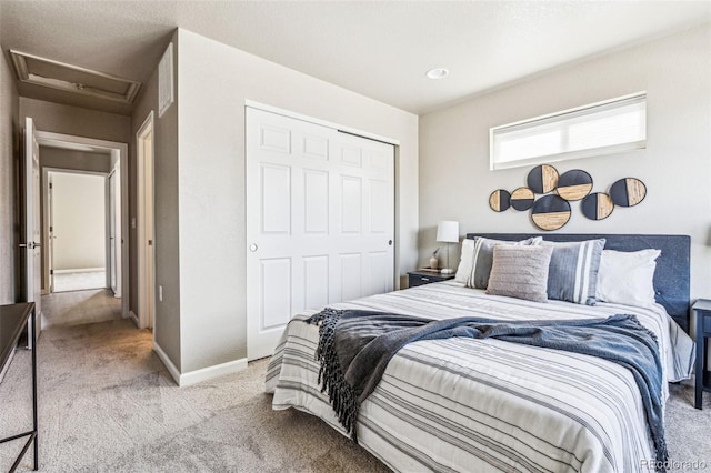 bedroom with carpet floors, a closet, attic access, and baseboards