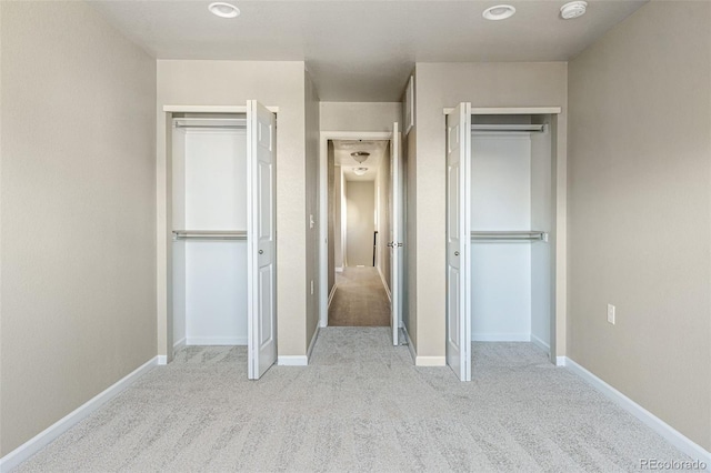 unfurnished bedroom with multiple closets, carpet floors, and baseboards