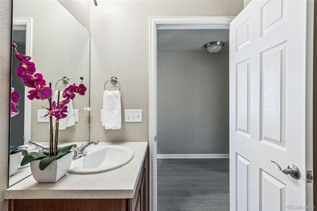 bathroom featuring vanity, baseboards, and wood finished floors