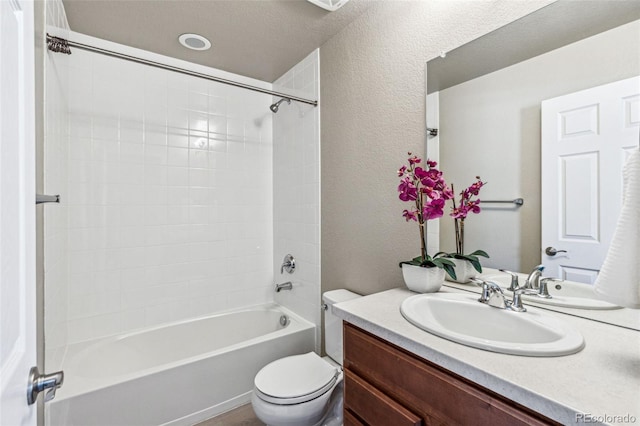 full bathroom with washtub / shower combination, a textured wall, vanity, and toilet