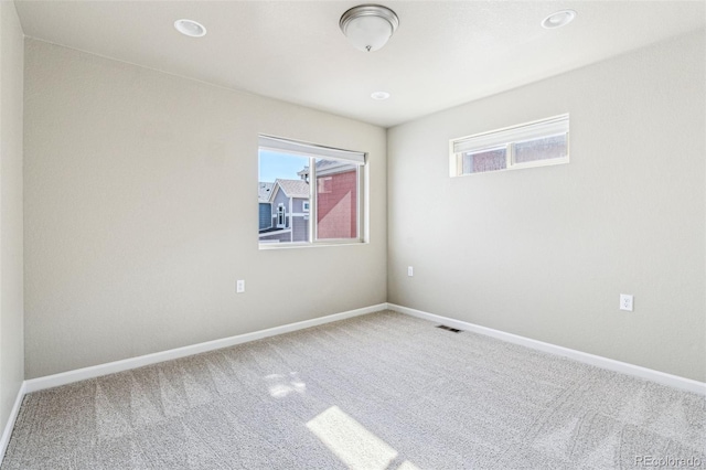 carpeted spare room featuring recessed lighting, visible vents, and baseboards